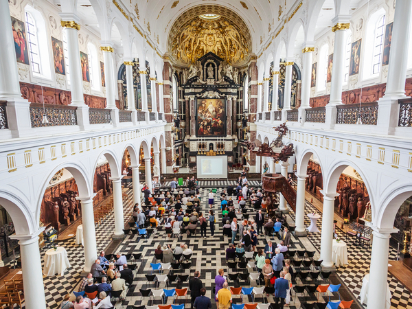 Tientallen mensen kijken in de Sint-Carolus Borromeuskerk maken zich op voor de schilderijwissel. Tientallen mensen kijken in de Sint-Carolus Borromeuskerk maken zich op voor de schilderijwissel.